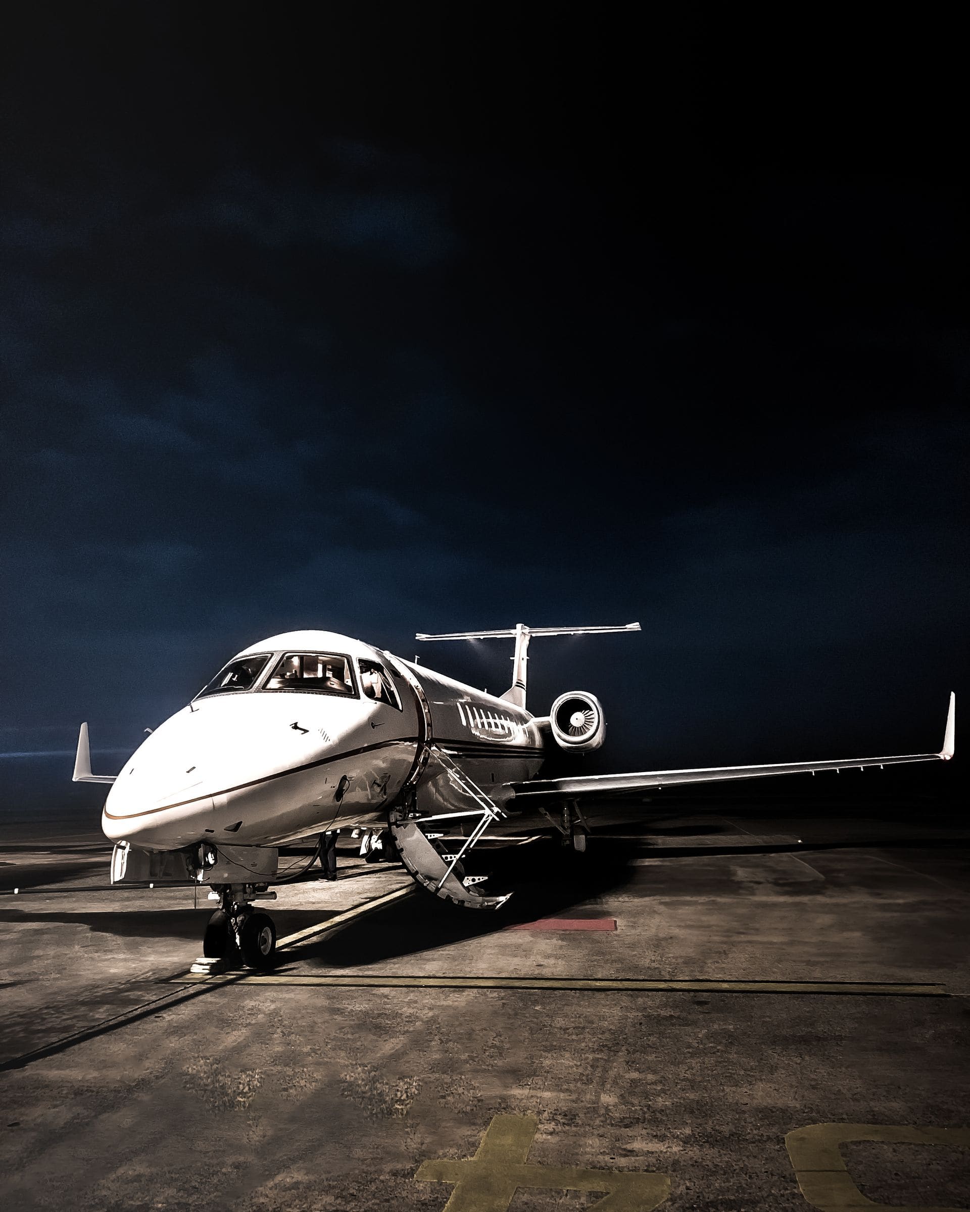 A private jet on a dark tarmac at night with its air-stairs lowered.