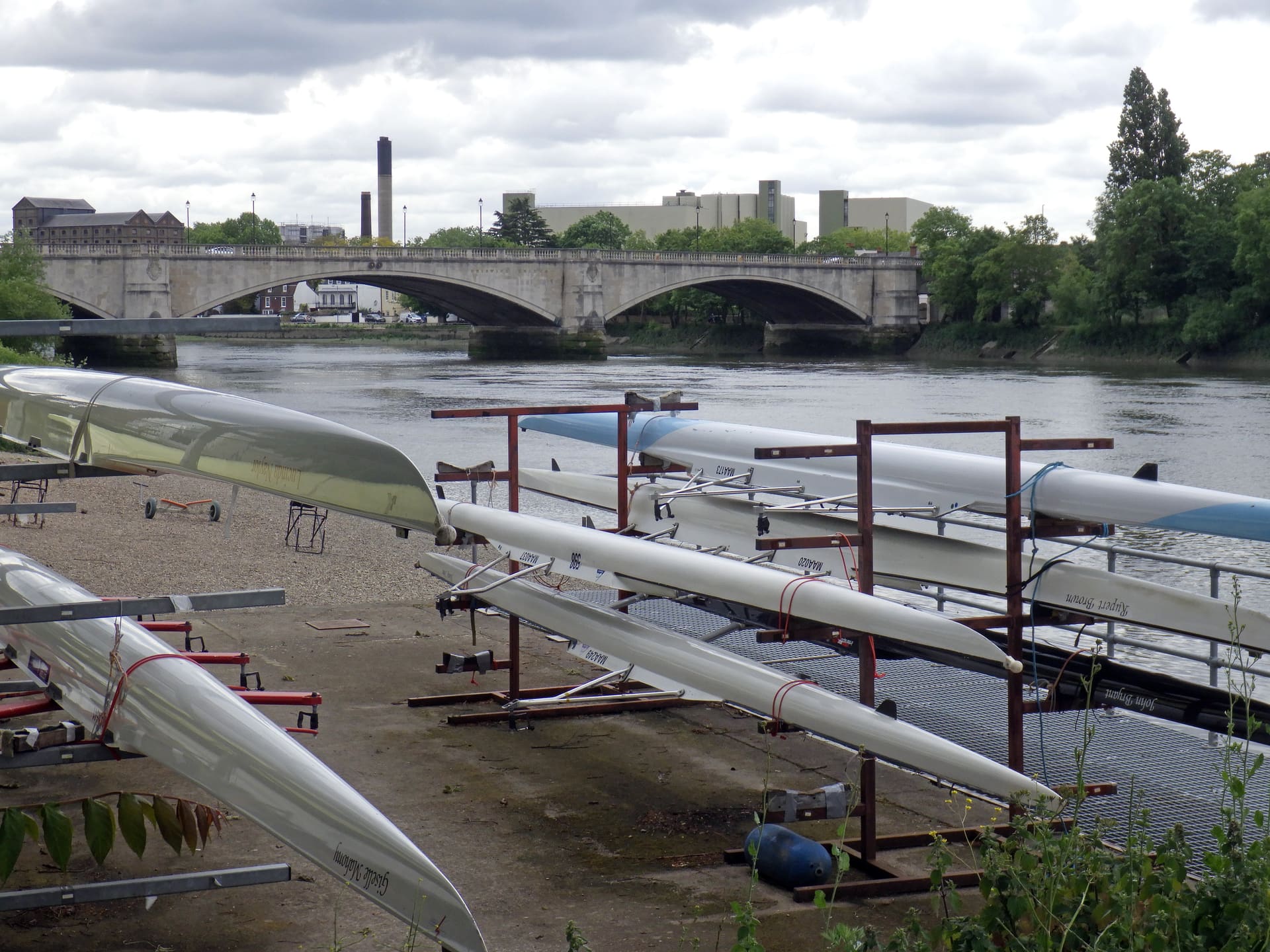 Racked rowing boats beside Chiswick Bridge on the Thames.