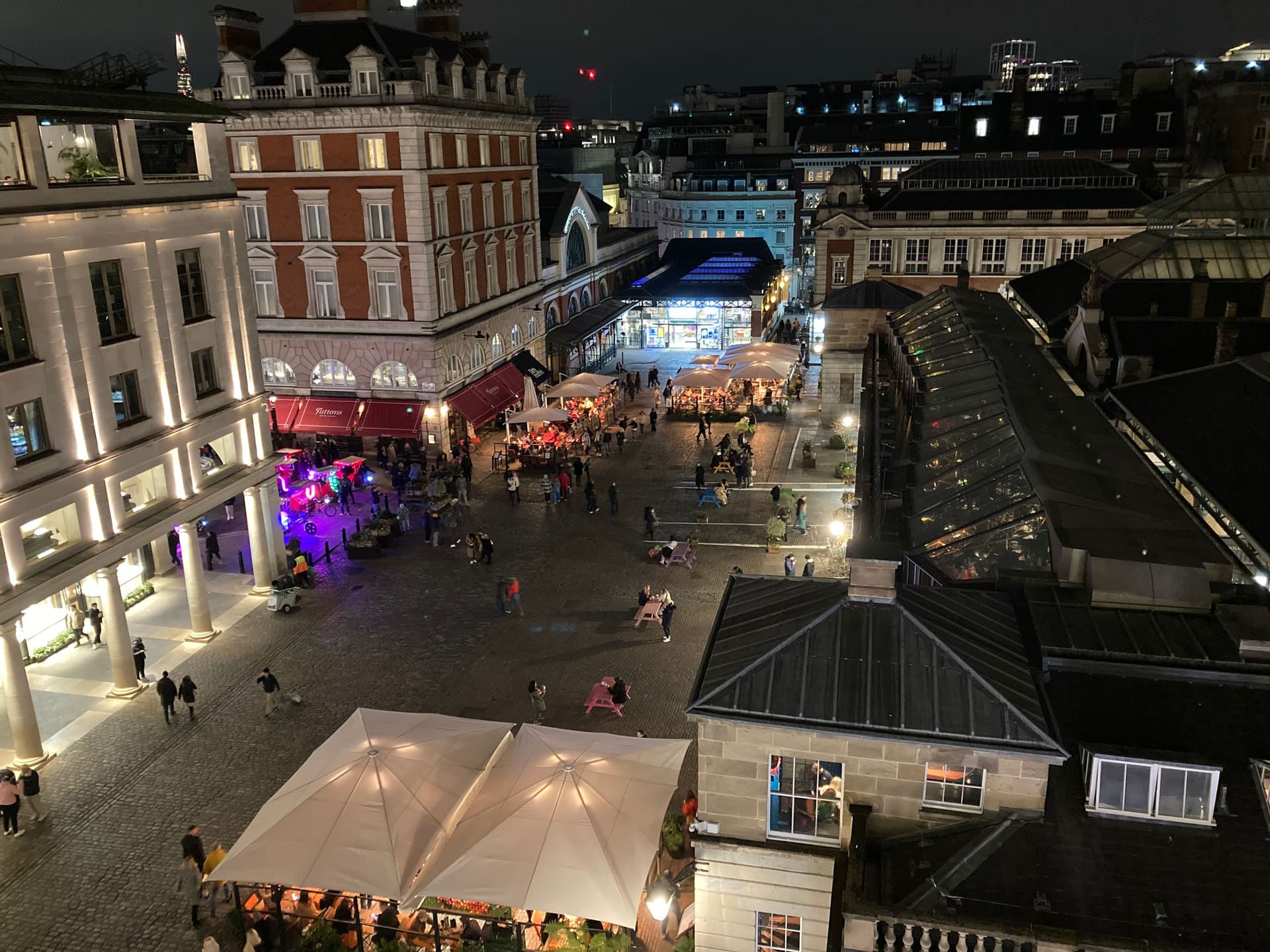 The Covent Garden piazza and market roofs lit in the evening.