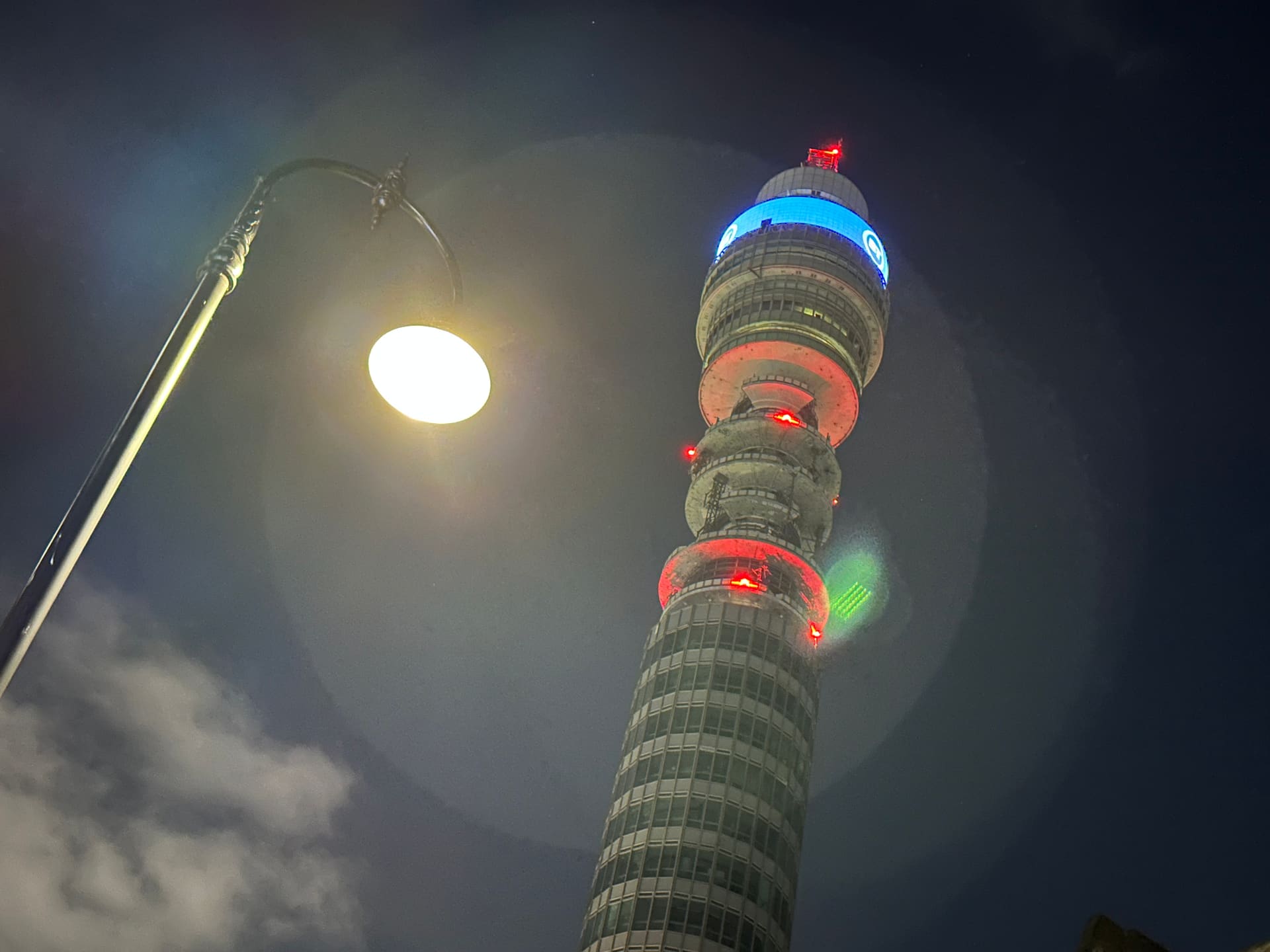 The BT Tower lit at night above a Fitzrovia street lamp.