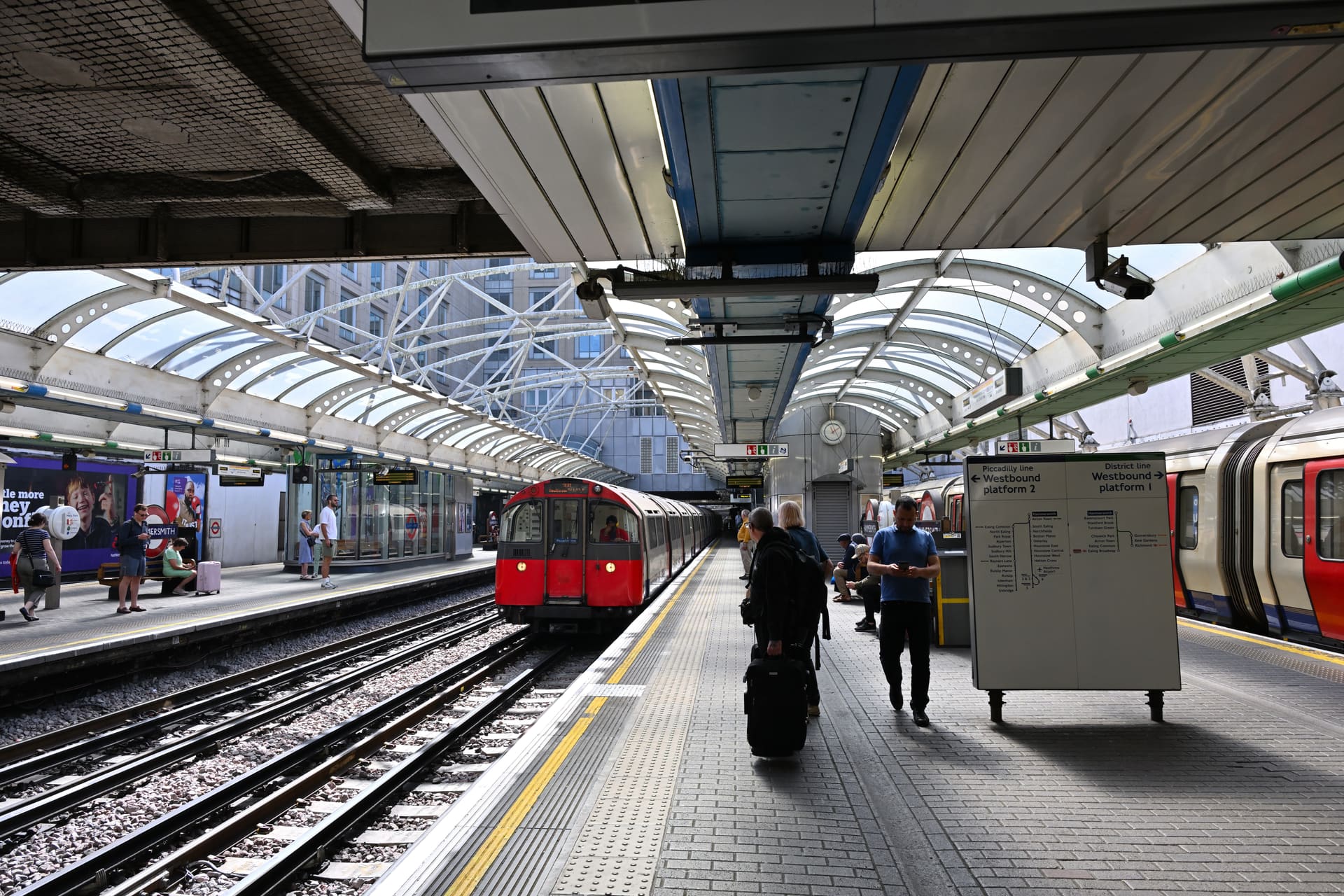 A Piccadilly line train arriving under the iron canopy at Hammersmith station.