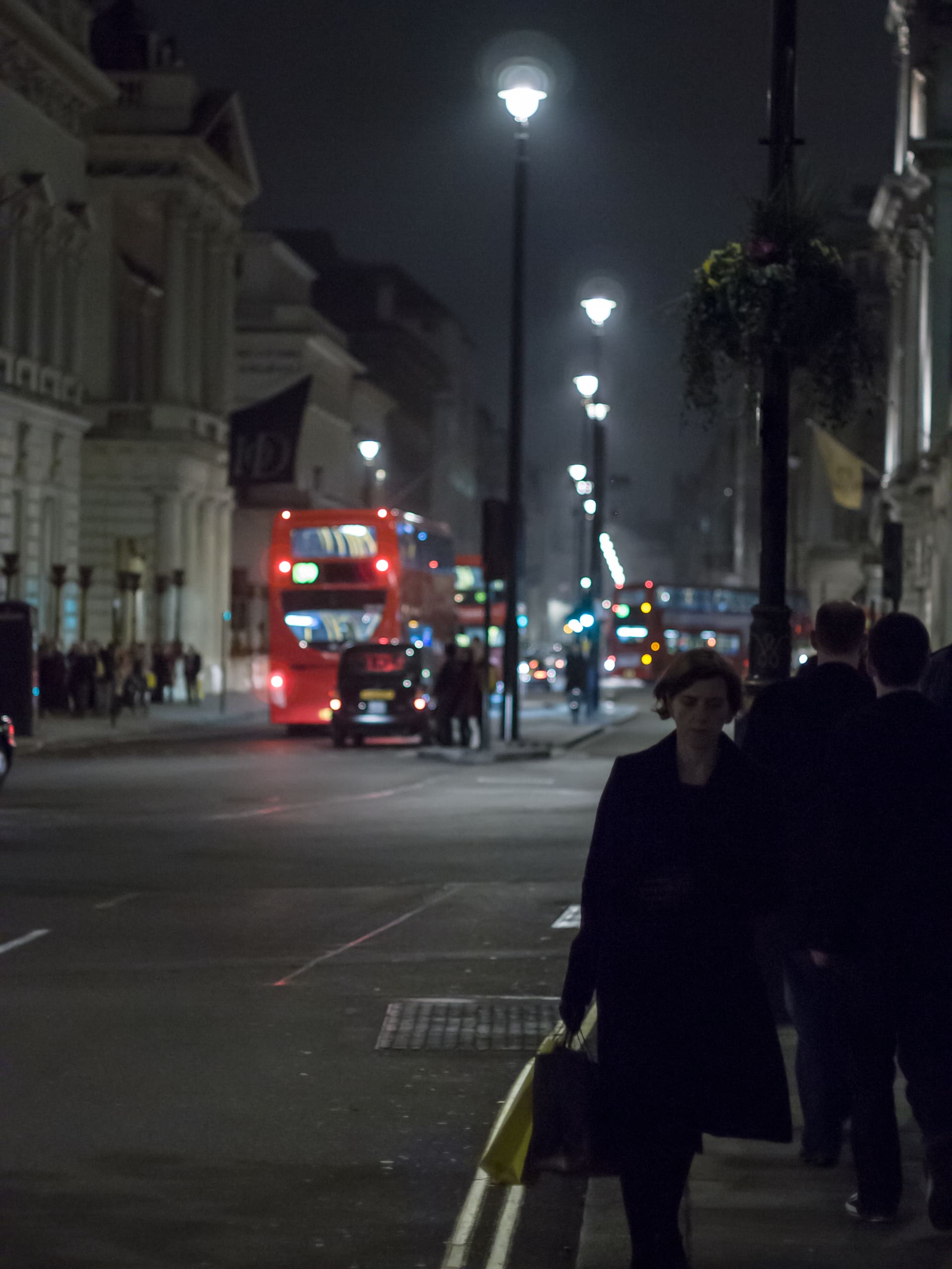 A London bus and street lamps on a wet Pall Mall at night.