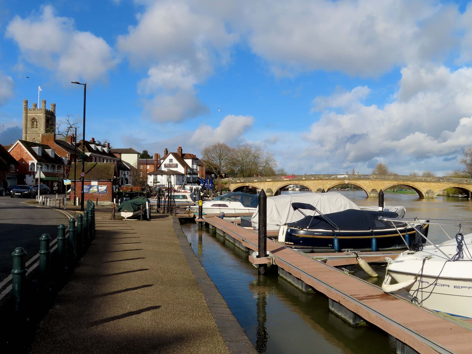 Boats moored on the Thames at Henley, the bridge and church tower beyond.