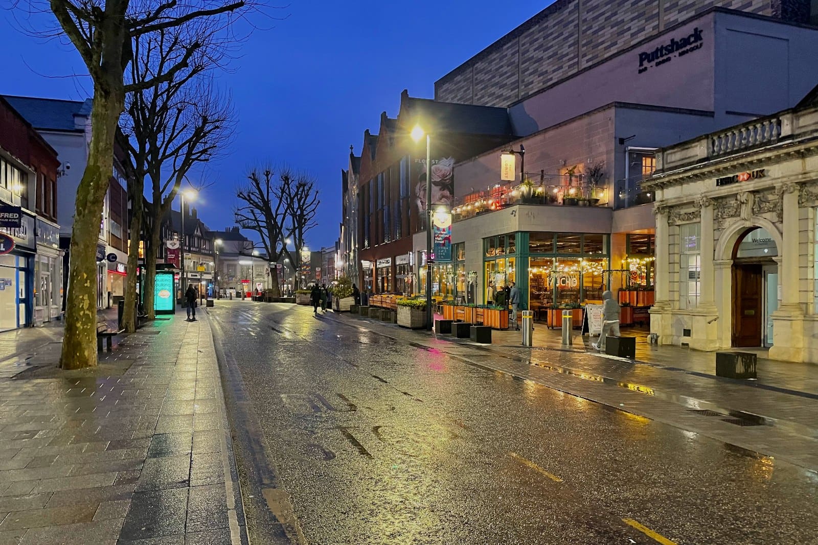 Watford High Street shining in the rain at dusk.