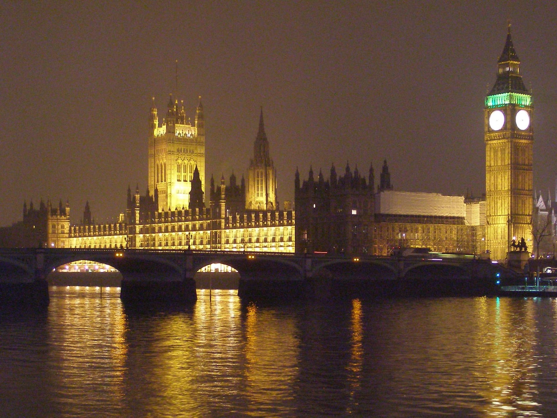 The Houses of Parliament floodlit at night above Westminster Bridge.